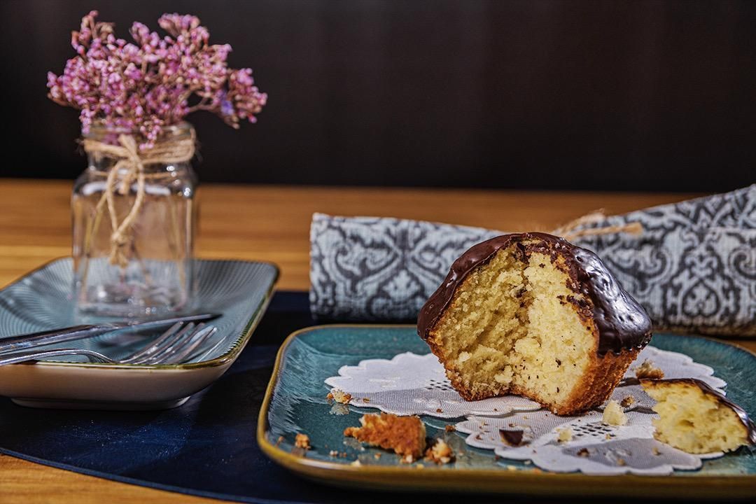 Muffin de chocolate con arándanos, menta y trozos de chocolate en un plato, con un cartel escrito a mano.