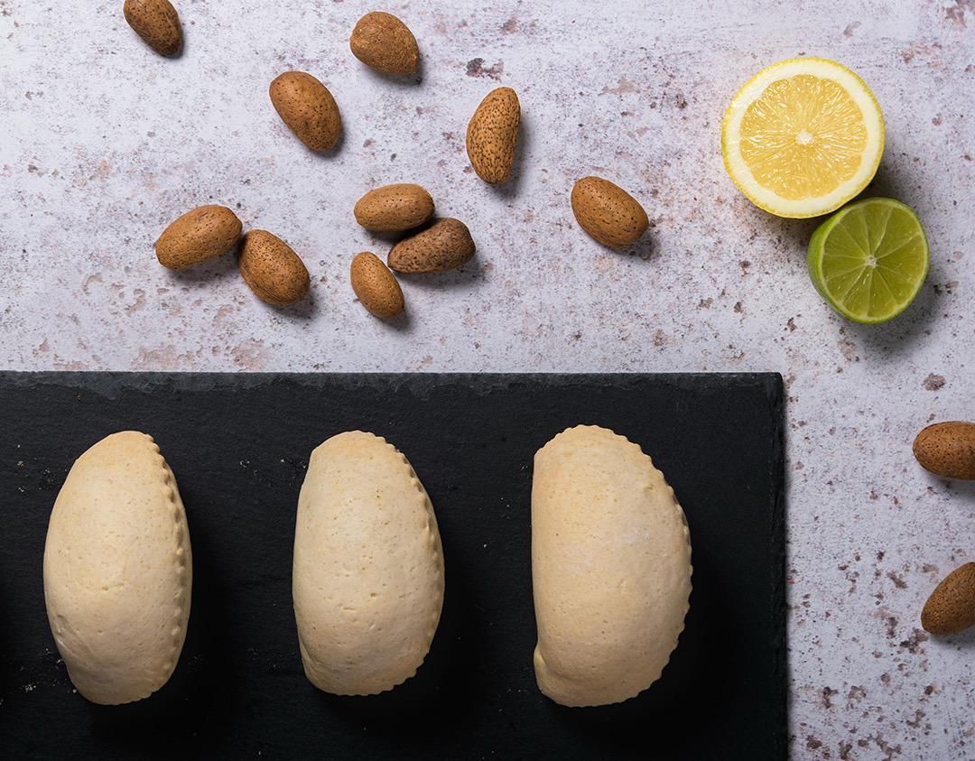Primer plano de pasteles en espiral espolvoreados con azúcar, con frambuesas y panecillos sobre una superficie oscura.