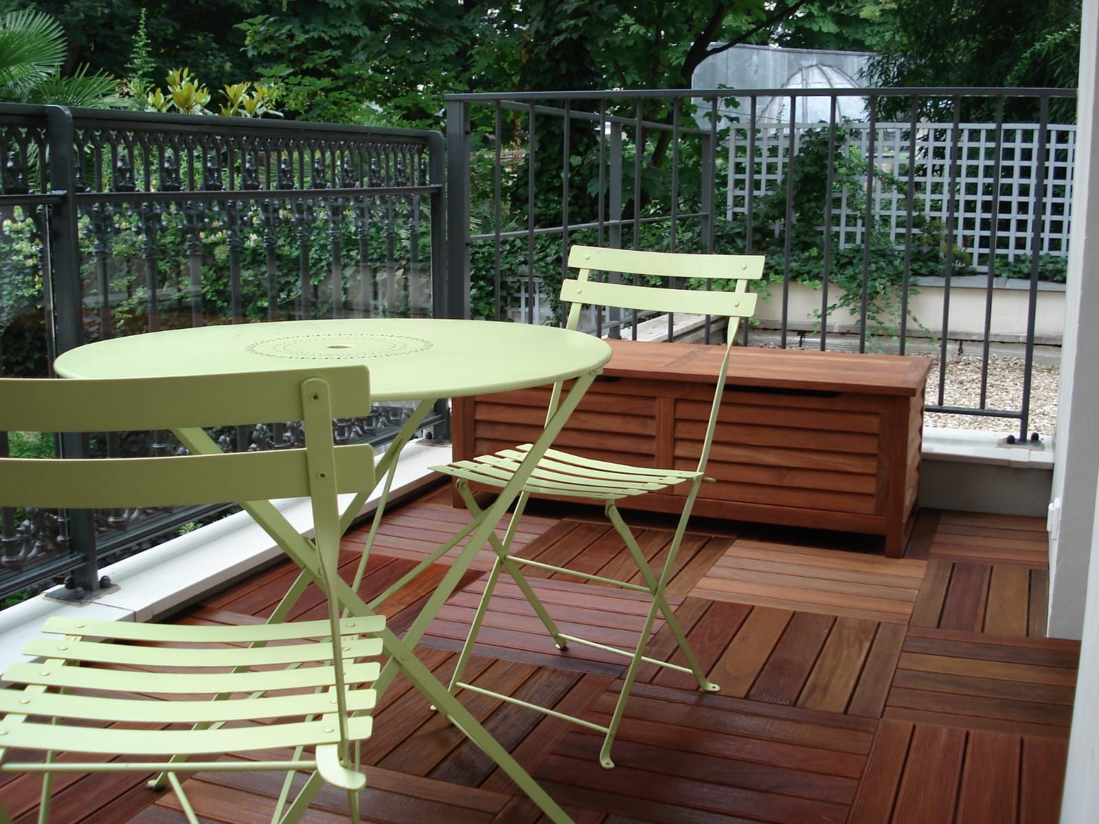Photo d'une terrasse en bois avec une table et deux chaises vertes