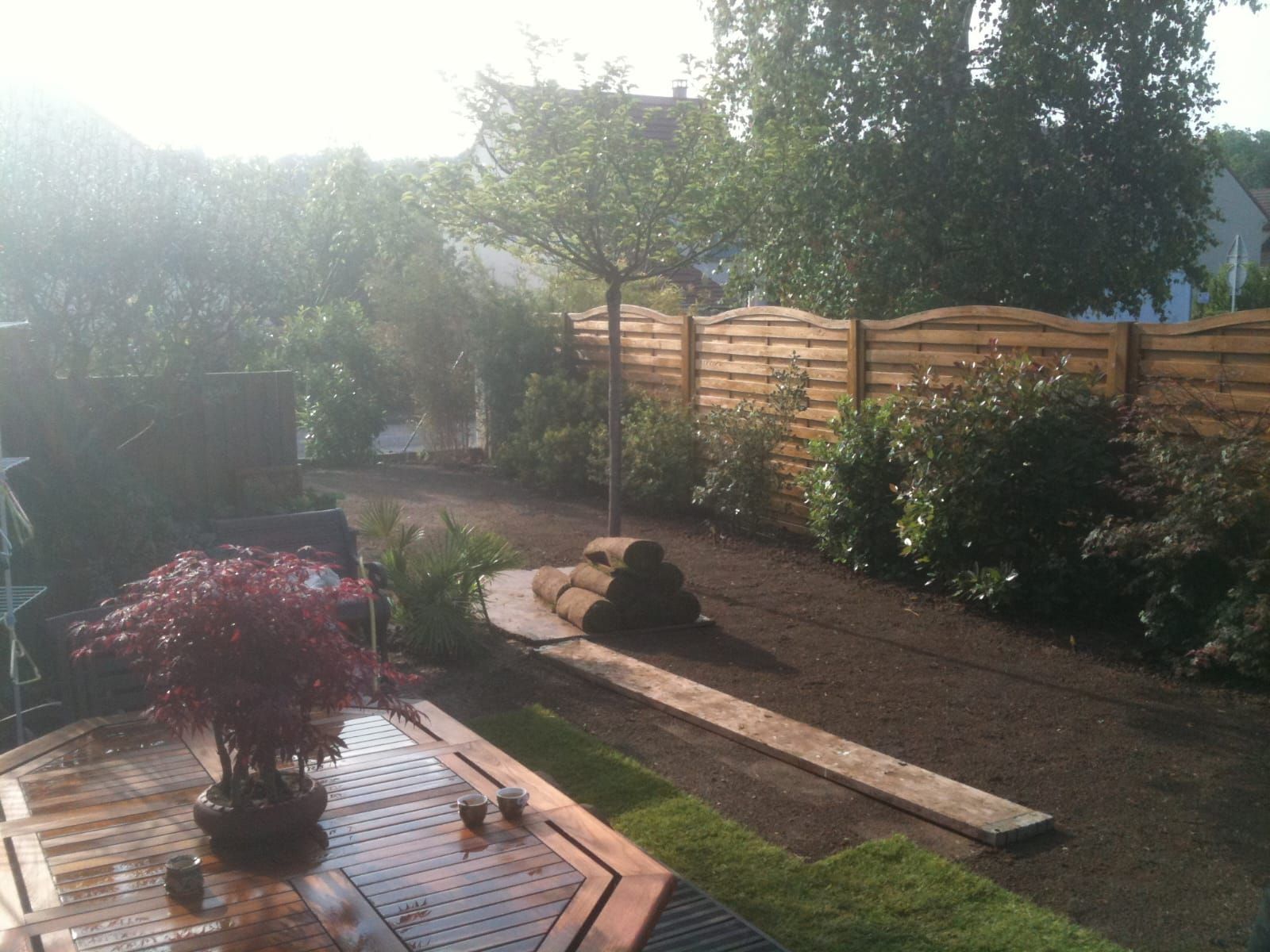 Photo d'un jardin avec une terrasse en bois et des arbustes 