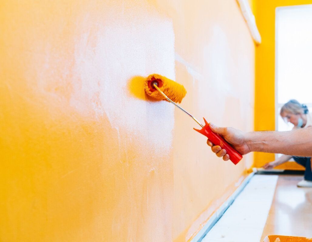 Una persona está pintando una pared con un rodillo de pintura.