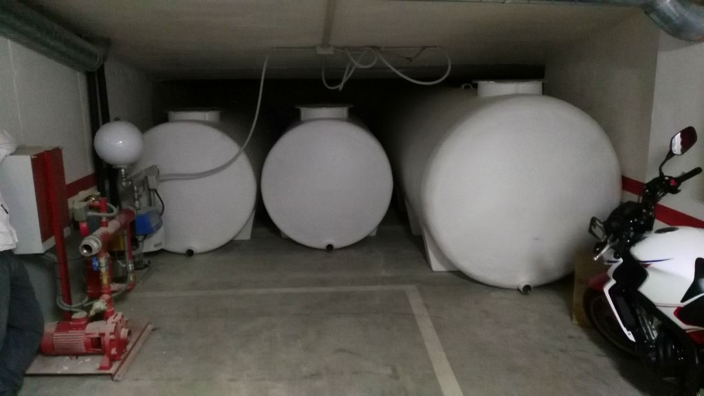 Tres tanques blancos están estacionados en un garaje al lado de una motocicleta.