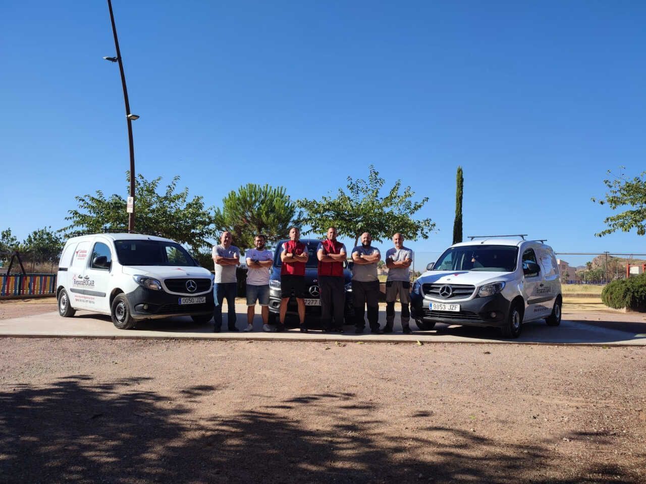 Un grupo de hombres de pie frente a una fila de furgonetas.