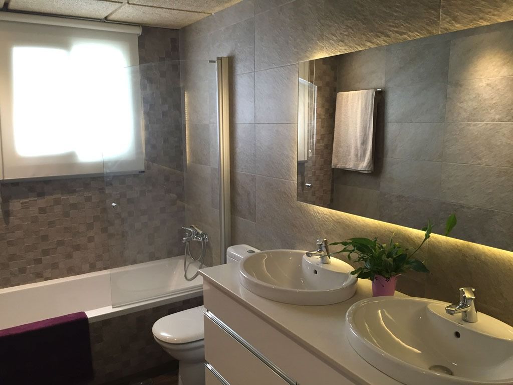 Un baño con dos lavabos, un inodoro, una bañera y un espejo.