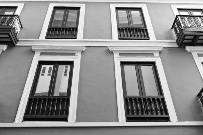 Vista en blanco y negro de la fachada de un edificio con múltiples ventanas y balcones de hierro forjado.