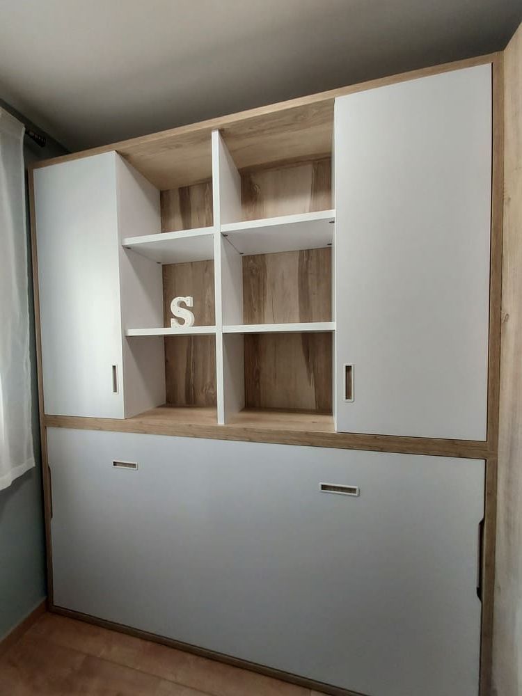 Armario blanco de pared con estantes abiertos y cama abatible. Acabado en madera clara.