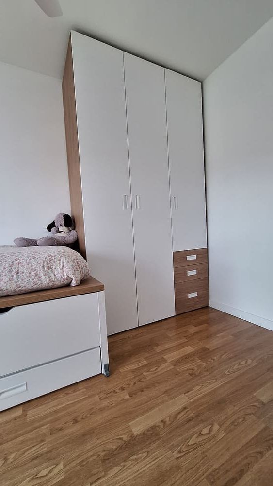 Una habitación infantil con paredes blancas y una gran ventana.