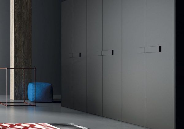 Un dormitorio con un gran armario y una otomana azul.