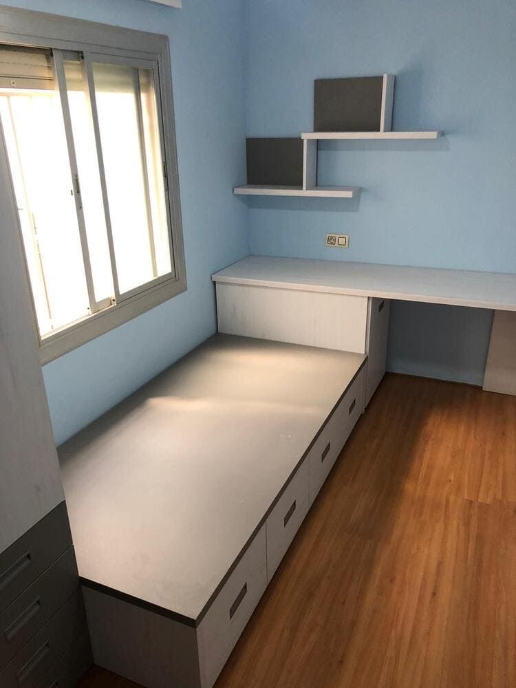 Un dormitorio con una cama con cajones y una cómoda.