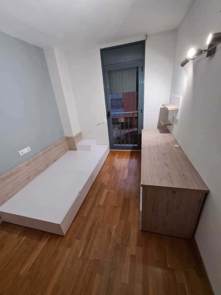 Un dormitorio con una cama y un escritorio con una computadora portátil encima.