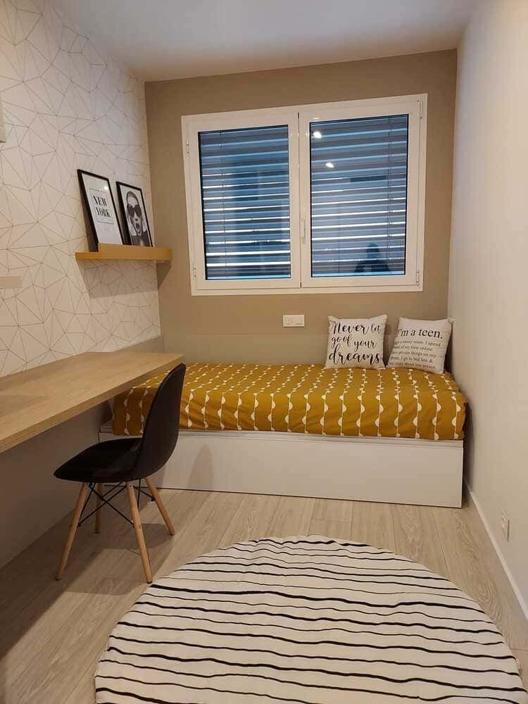 Una habitación infantil con paredes blancas y una gran ventana.