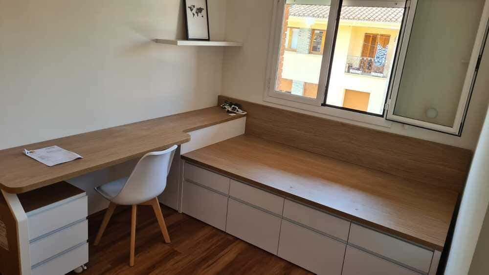 Un dormitorio con una cama con cajones y una cómoda.