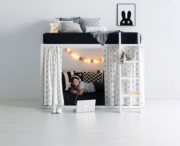 Una persona está acostada debajo de una litera con una computadora portátil en el suelo.