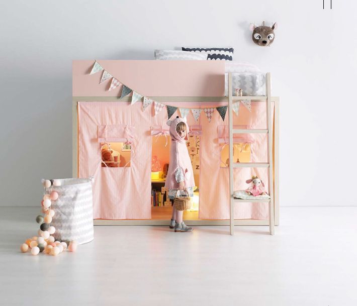 Una niña está parada en una tienda de campaña rosa debajo de una litera.