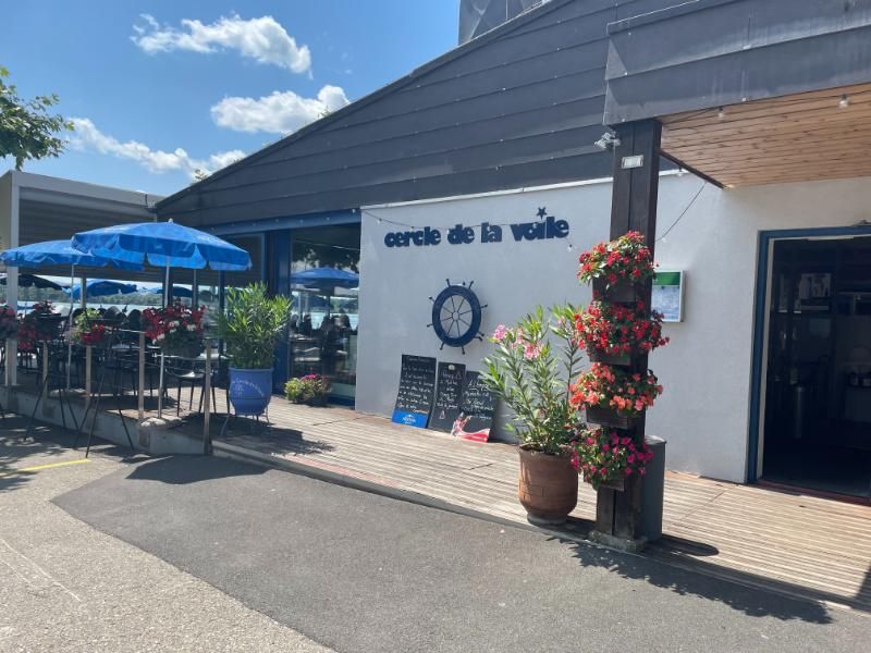 Le restaurant avec des parasols bleus et des fleurs devant.