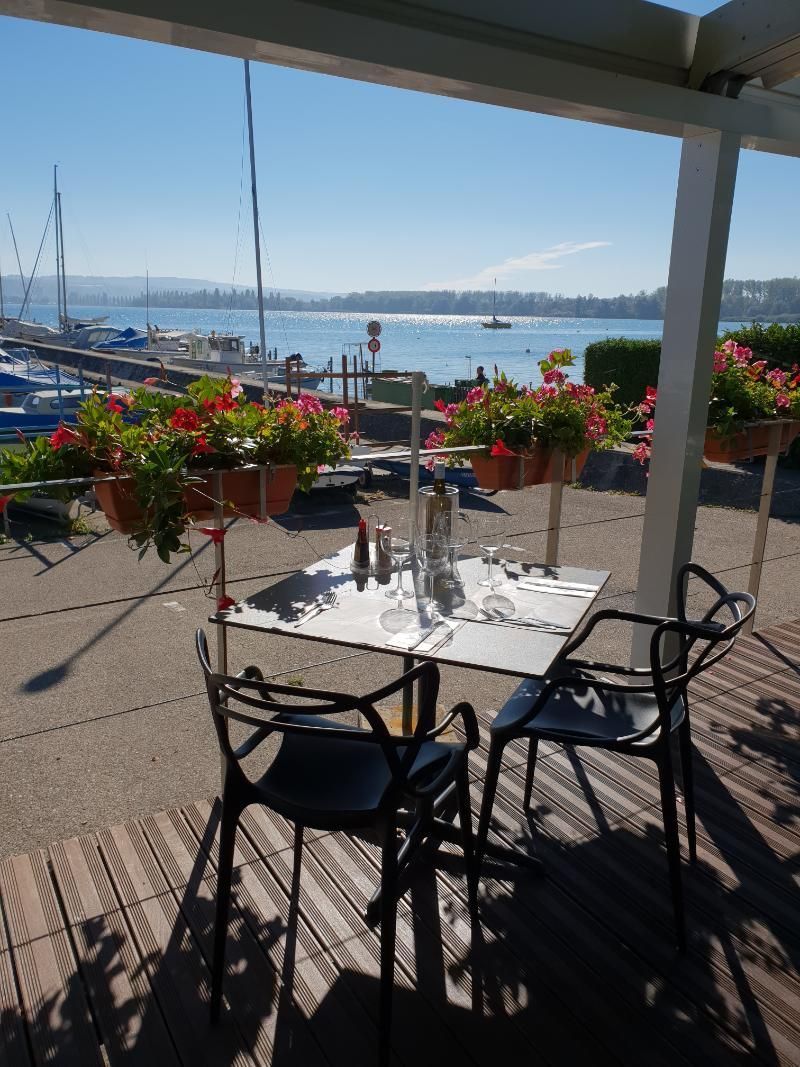 Une table et des chaises sur une terrasse donnant sur le lac
