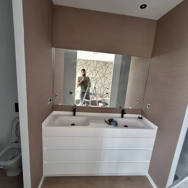Un baño con dos lavabos y un espejo grande.