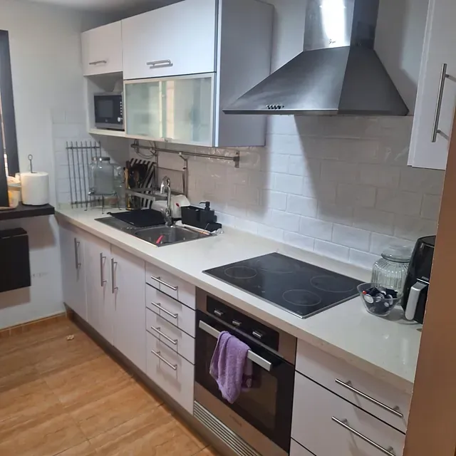 Una cocina con gabinetes blancos y un horno de estufa.