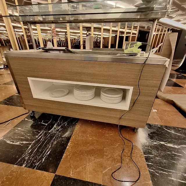 Una mesa de buffet con platos está colocada sobre un suelo a cuadros.