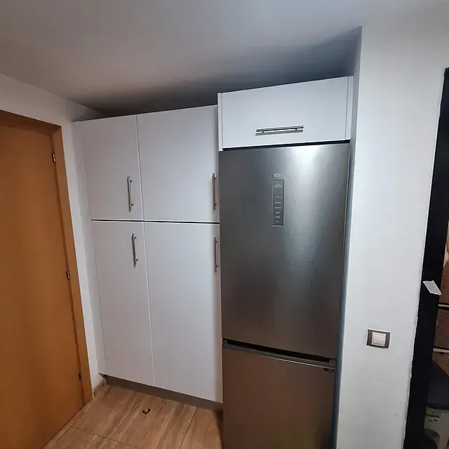 Una cocina con refrigerador de acero inoxidable y gabinetes blancos.