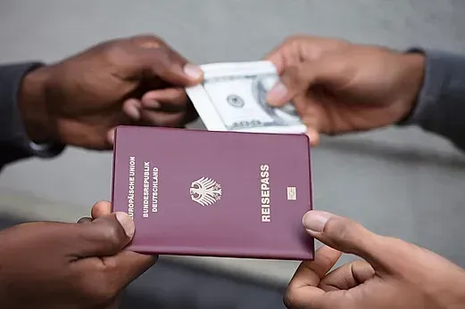 Un hombre le da a otro hombre un pasaporte y un billete de dólar.