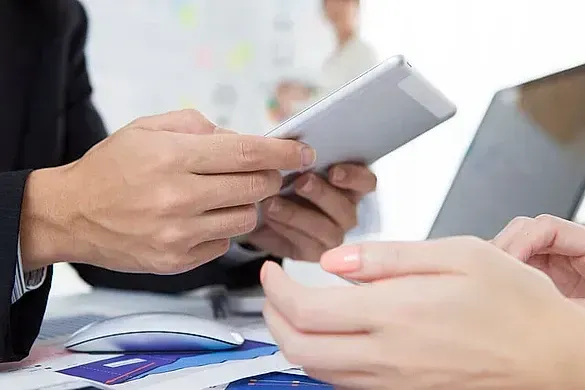 Un hombre sostiene un teléfono celular y una mujer sostiene una tableta.