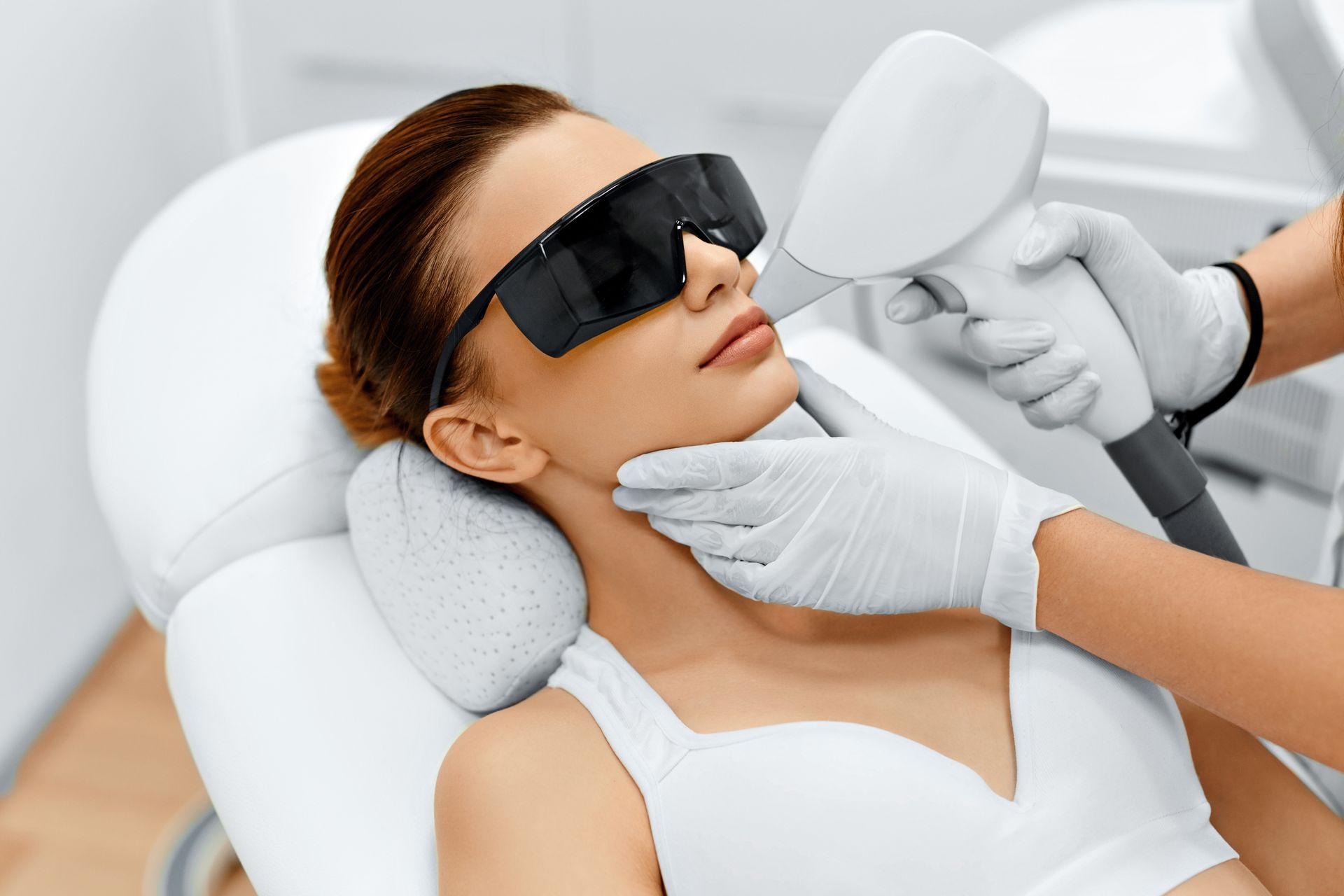 Traitement oculaire au laser en cours, le patient portant des lunettes de protection et le clinicien utilisant un appareil portatif.