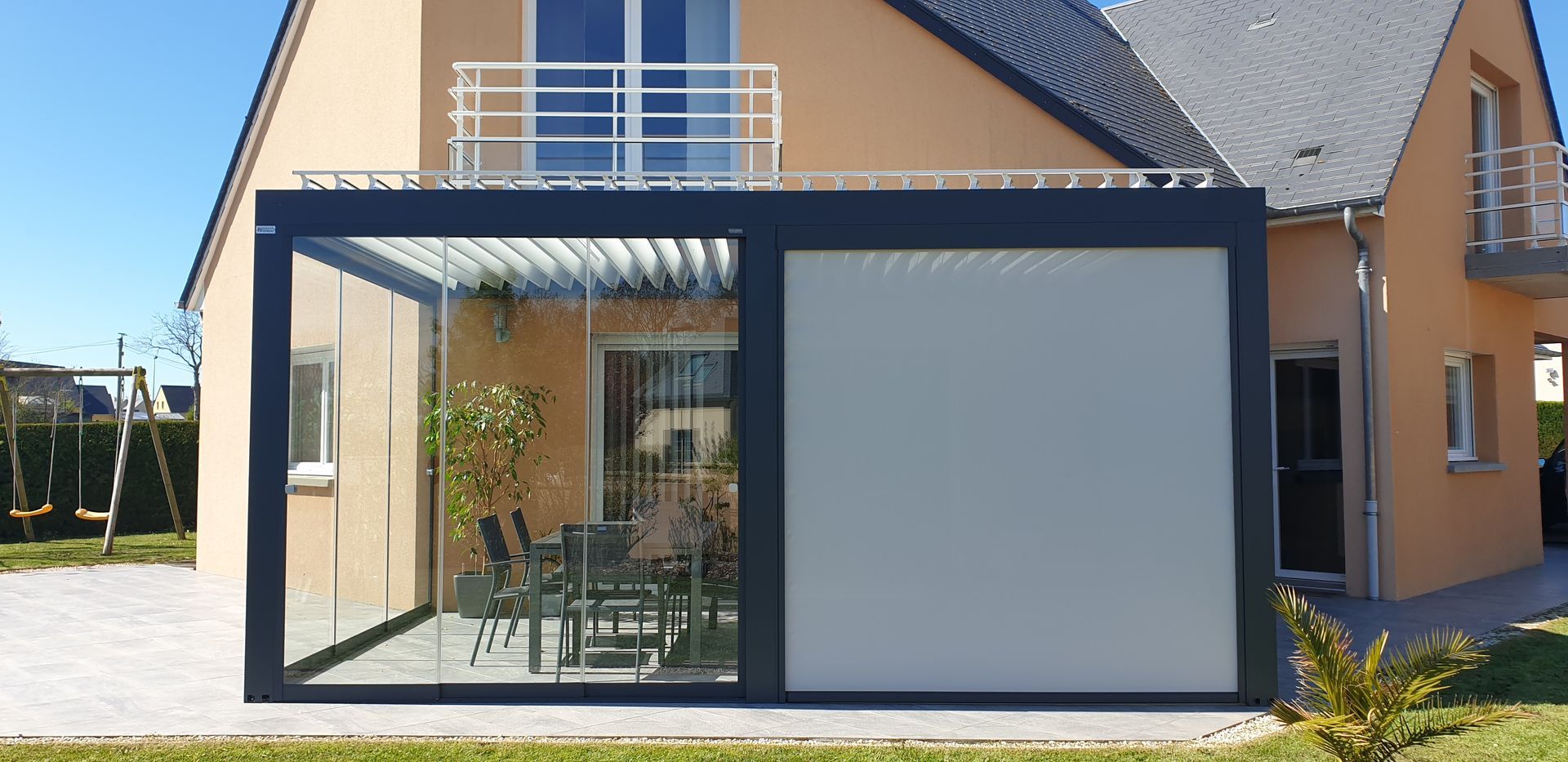 Véranda en verre et en pvc noir à moitié fermée