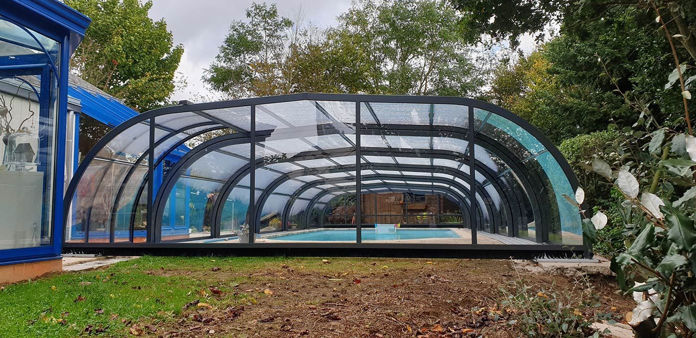 Abri de piscine semi-haut en aluminium noir devant une terrasse bleu