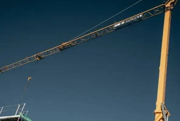 Baukran auf Baustelle bei Sanierungsarbeiten im Hochbau unter klarem Himmel Baukran auf Baustelle bei Sanierungsarbeiten im Hochbau unter klarem Himmel