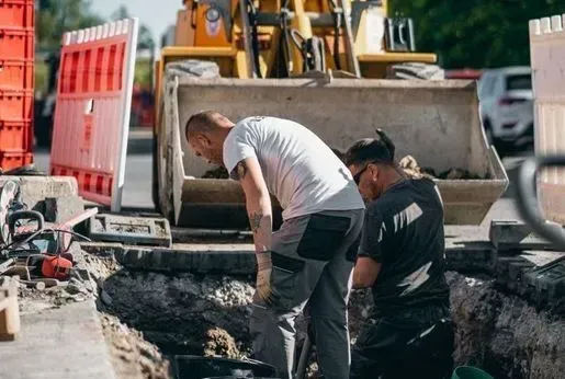 Tiefbauarbeiten mit Bagger und Bauarbeitern auf Straßenbaustelle Tiefbauarbeiten mit Bagger und Bauarbeitern auf Straßenbaustelle