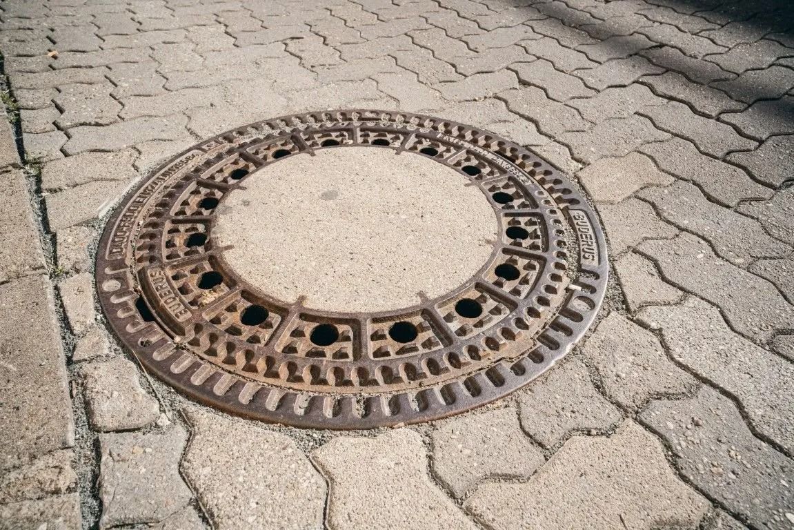 Kanaldeckel auf gepflasterter Fläche im Straßen- und Tiefbau
