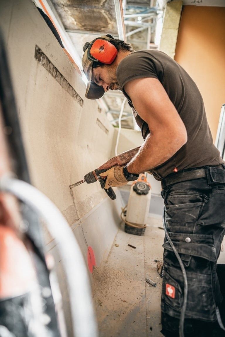 Handwerker bei Sanierungsarbeiten mit Schutzkleidung auf Baustelle