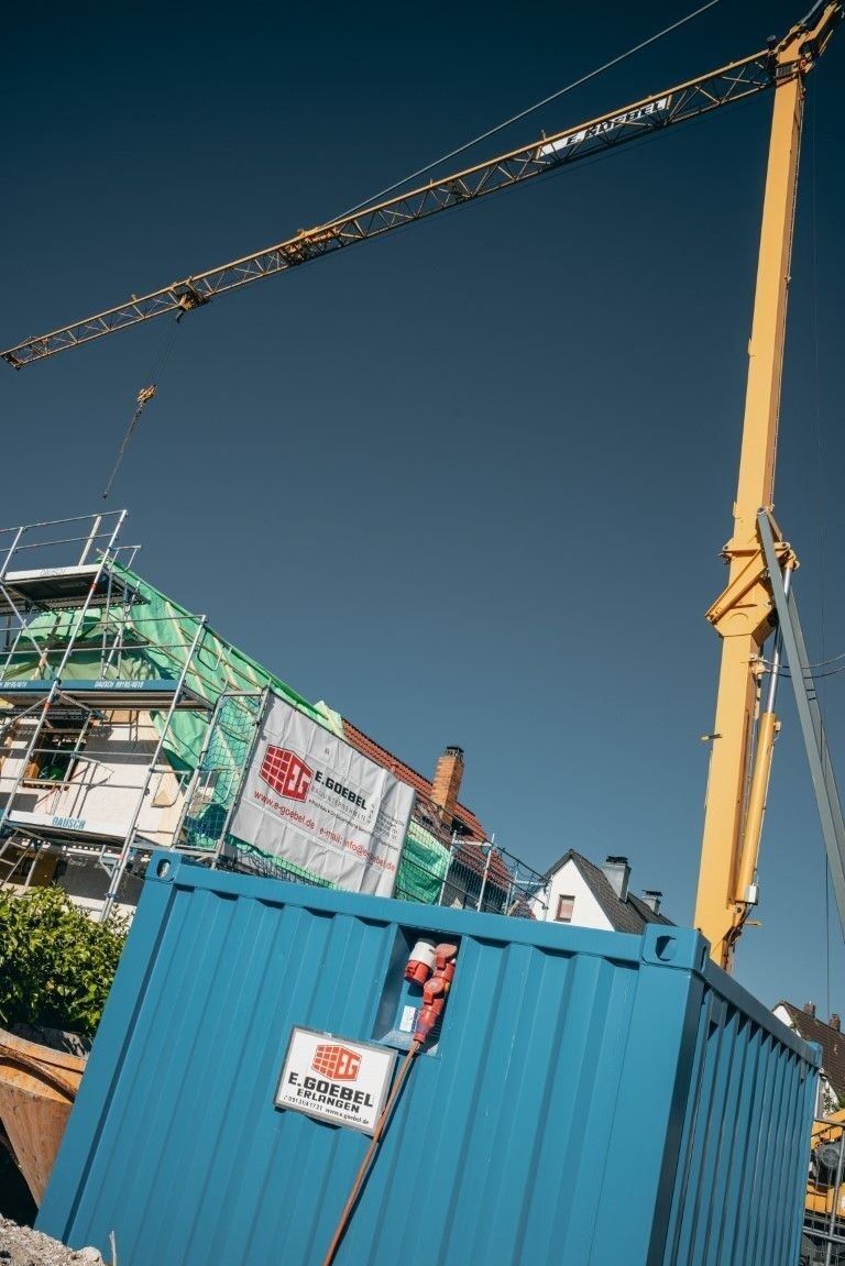 Baukran auf Baustelle bei Modernisierungsarbeiten im Hochbau unter blauem Himmel