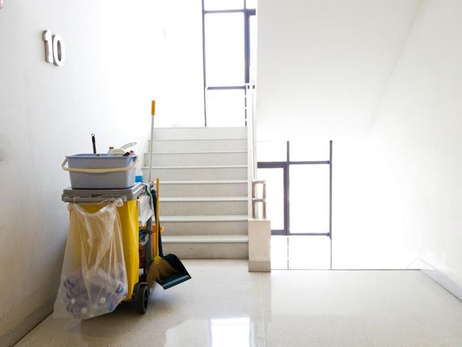 Escalier blanc avec chariot de nettoyage et produits d'entretien à côté des escaliers