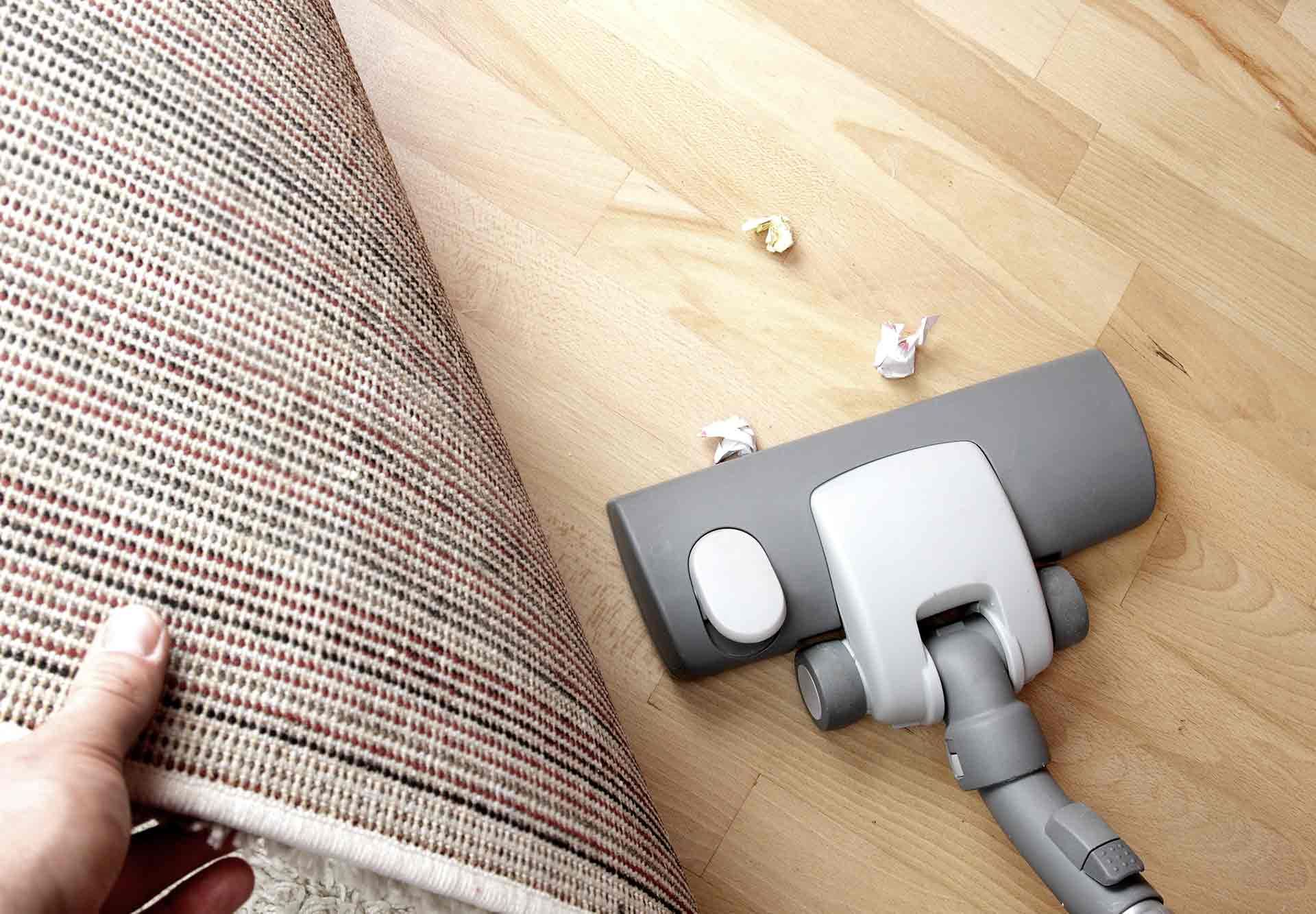 Aspirateur manuel pour enlever les miettes à côté d'un canapé beige sur un sol en bois