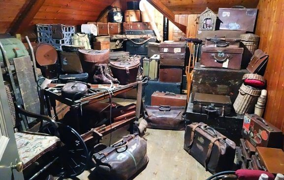Grenier encombré de valises, de malles et de boîtes vintage empilées sous un plafond en bois incliné