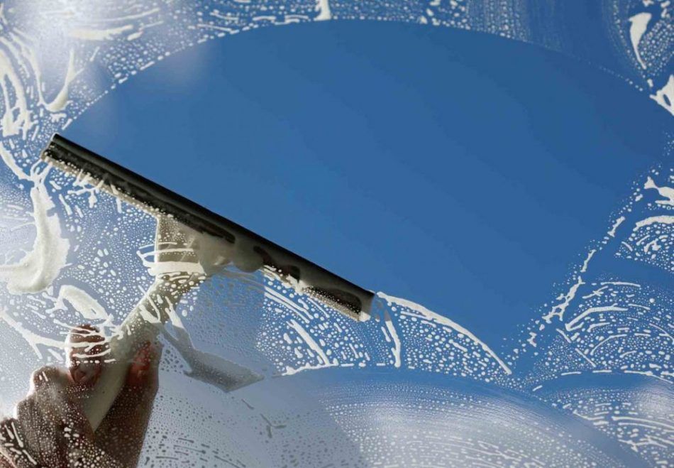 Fenêtre dont l'essuie-glace dégage partiellement le givre, révélant un ciel bleu au-dessus d'une surface enneigée.