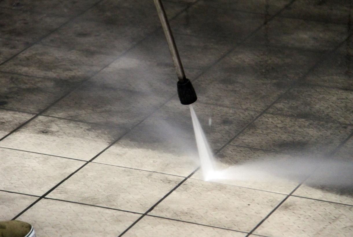Nettoyeur haute pression arrosant un trottoir carrelé
