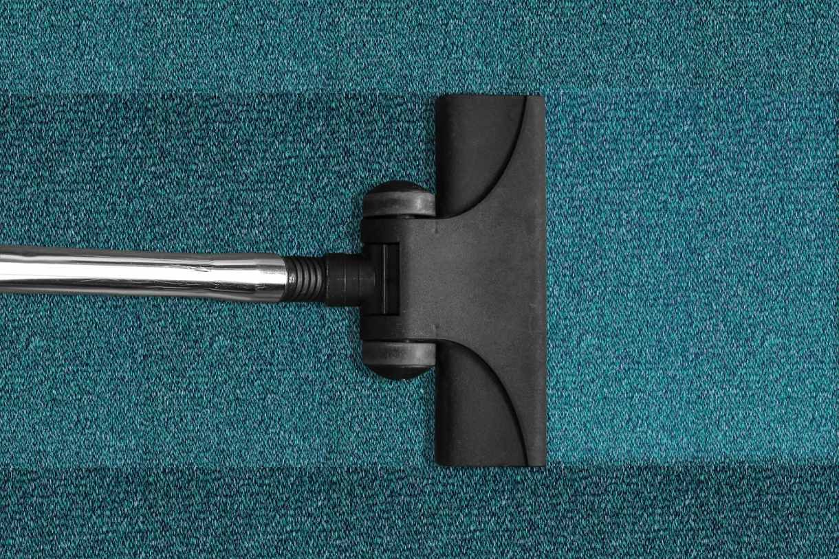 Embout d'aspirateur noir sur moquette turquoise avec tube métallique fixé