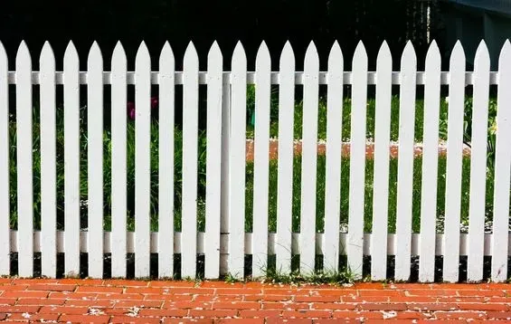 Una valla blanca está colocada encima de una pared de ladrillos.
