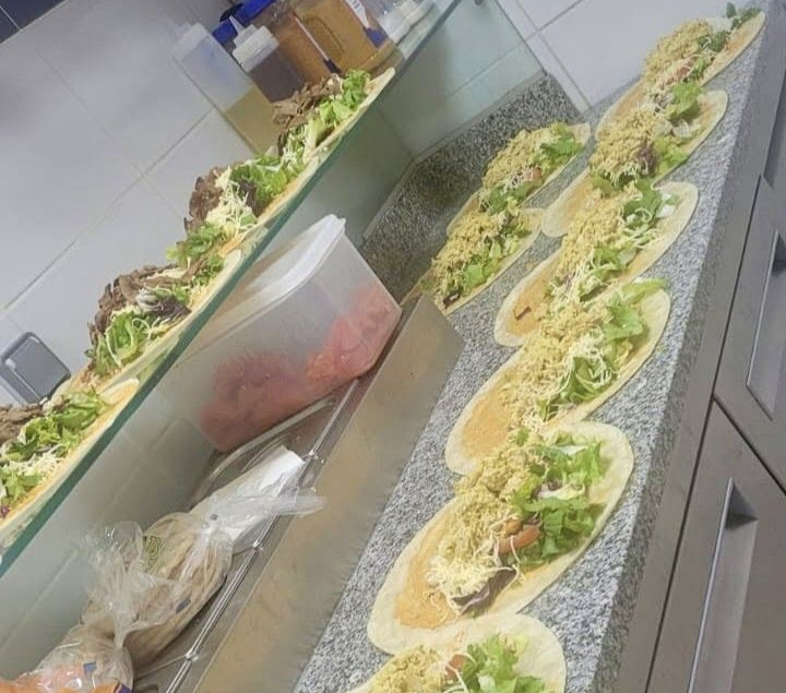 Deux sandwichs bien garnis sur du papier kraft, avec du bacon, du jambon, du fromage et des tomates.