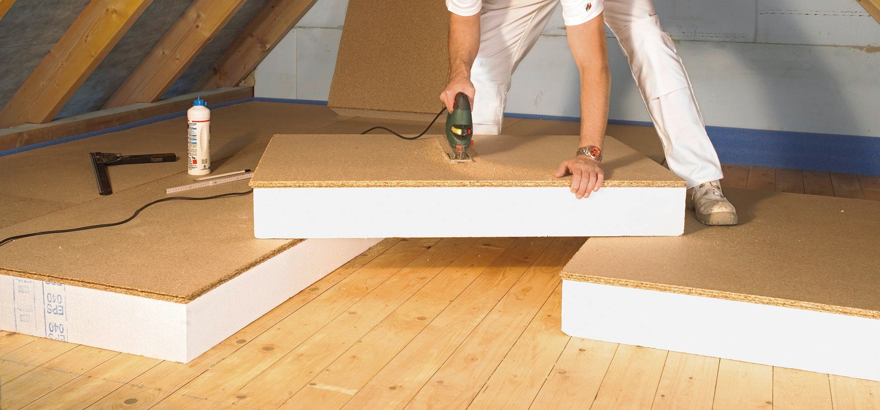 Handwerker verlegt Dämmplatten auf einem Dachboden.