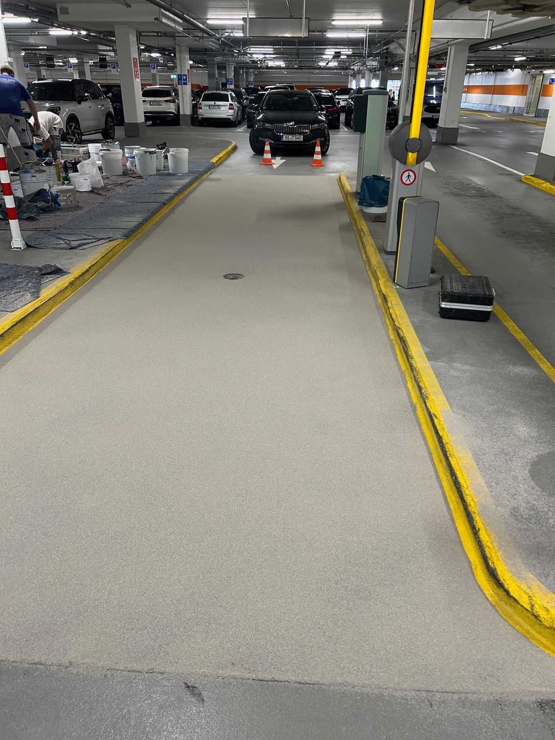 Markierte Fahrspuren und Arbeitsmaterialien in einer Parkgarage.