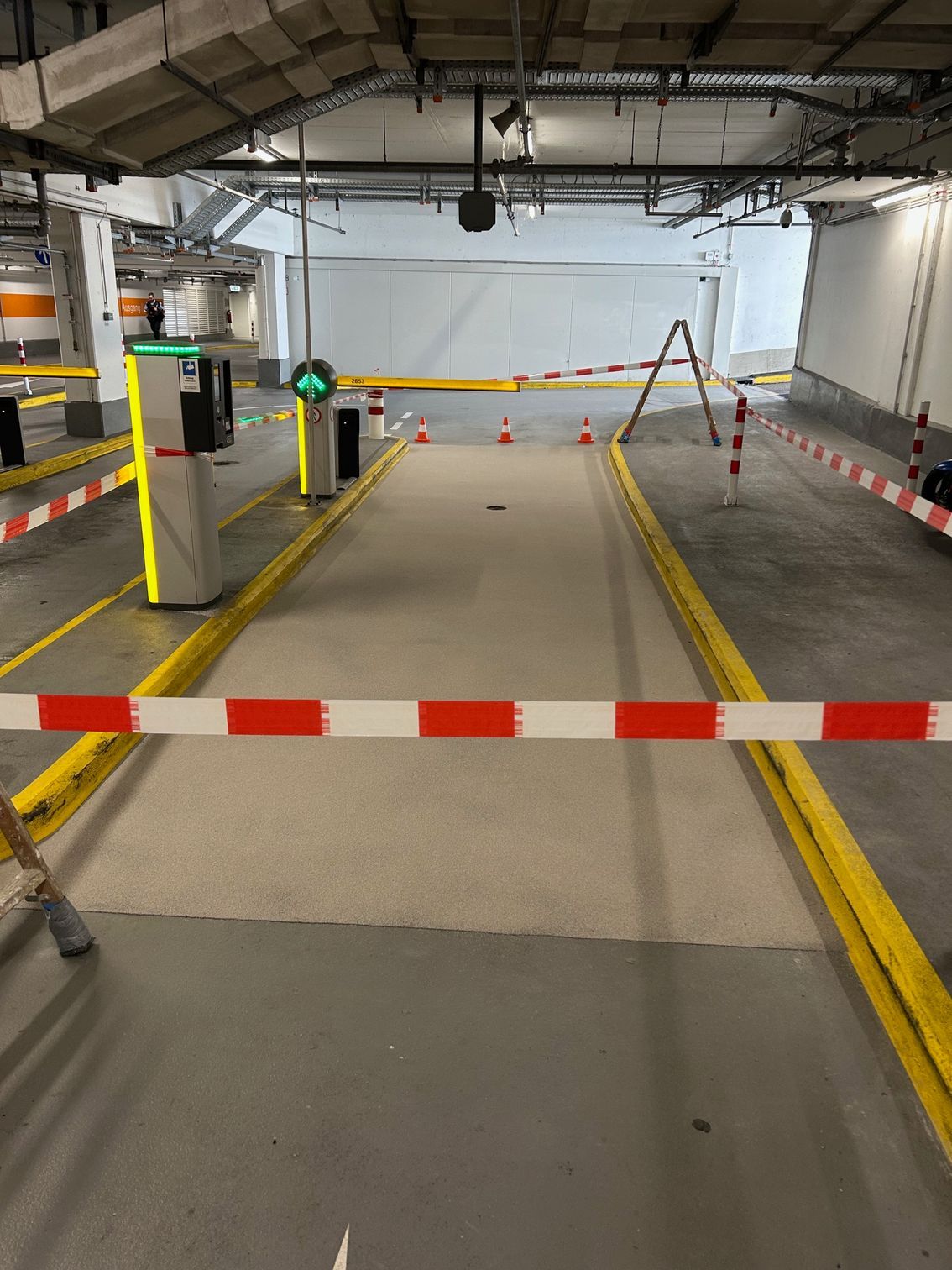 Sanierter Rampenbereich einer Tiefgarage mit technischer Deckeninstallation.
