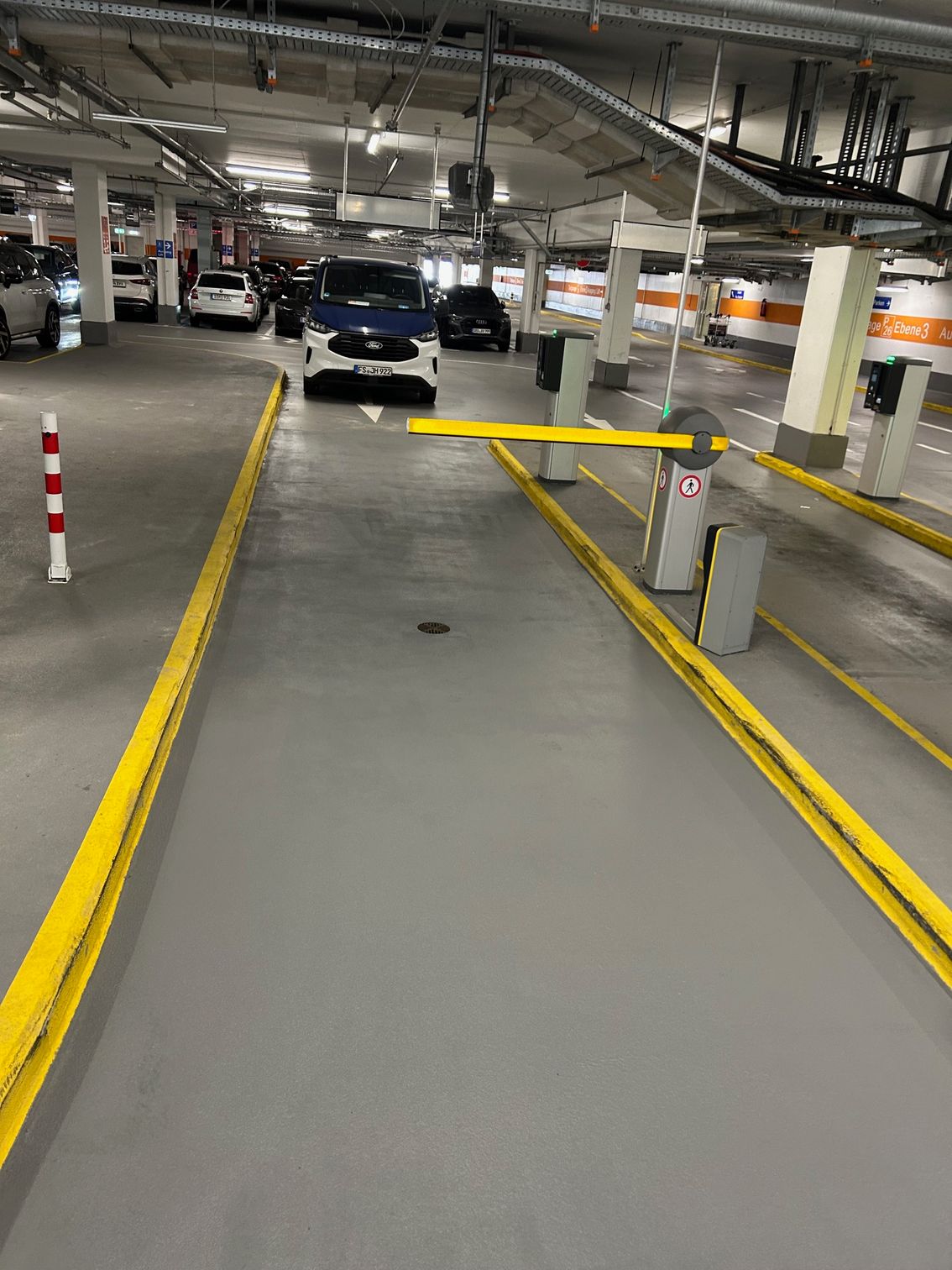 Einfahrtsschranke in einer sanierten Tiefgarage mit markierten Wegen.