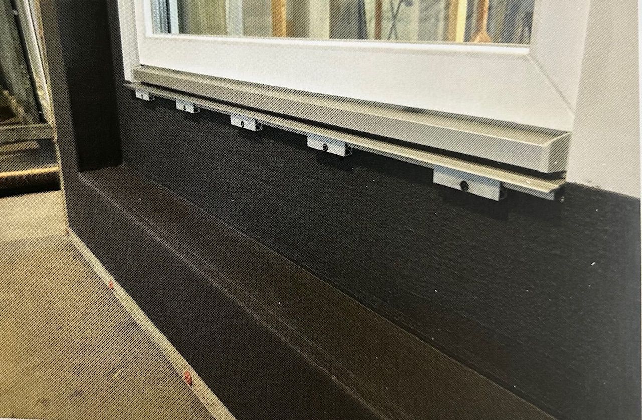 Detailansicht einer Bitumen-Abdichtung unter einem Fensterprofil.