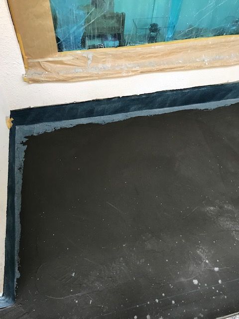 Abgeklebter Fensterbereich während Abdichtungsarbeiten am Sockel.