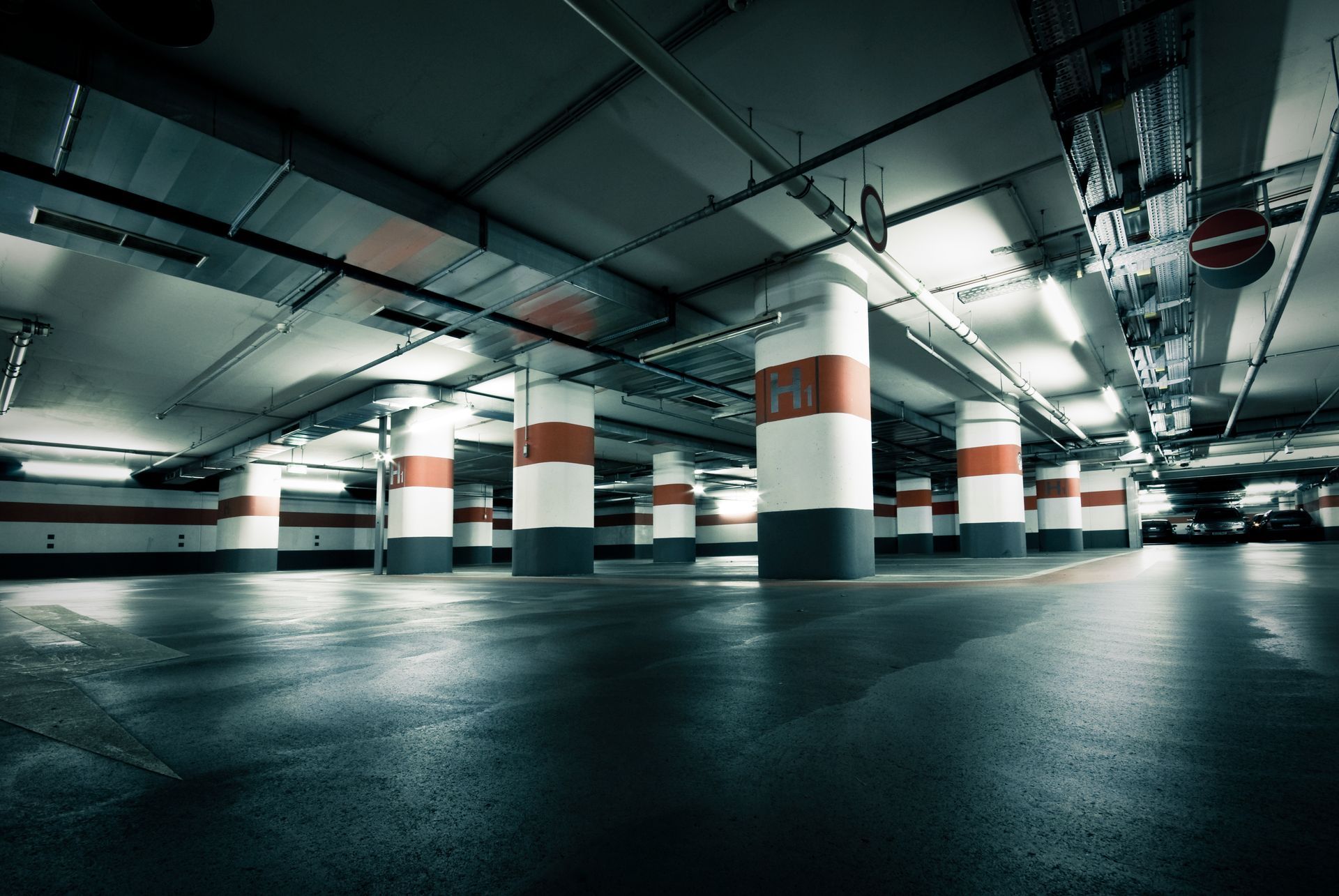 Moderne, hell beleuchtete Tiefgarage mit markierten Betonsäulen.