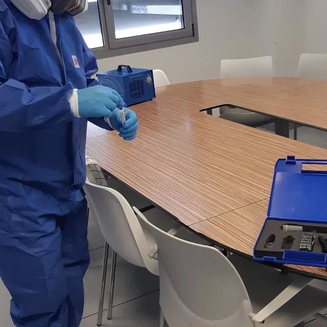 Un hombre con un traje azul está de pie frente a una mesa de madera.